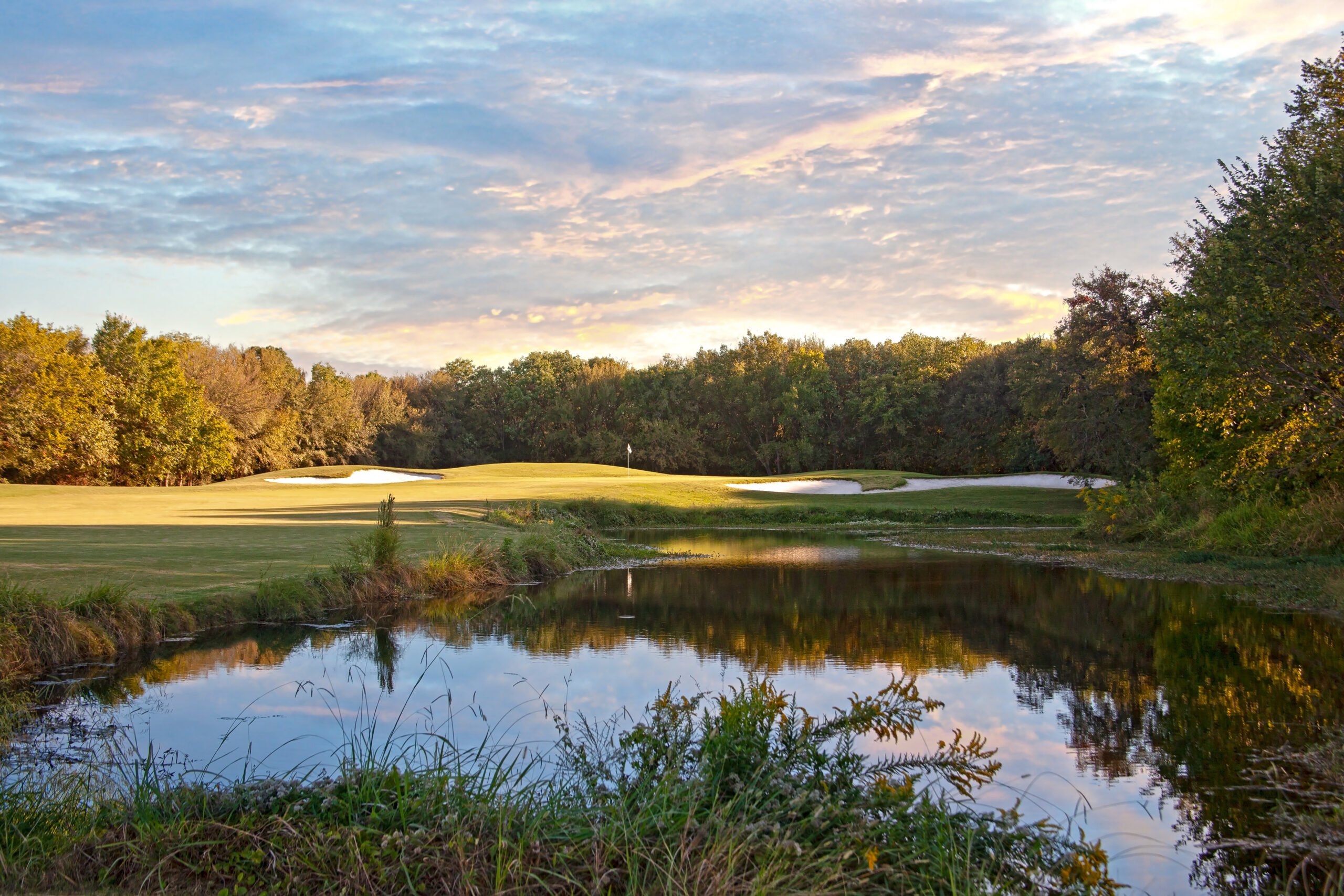 A view of Nature around a golf hole that is surrounded by beautiful trees.