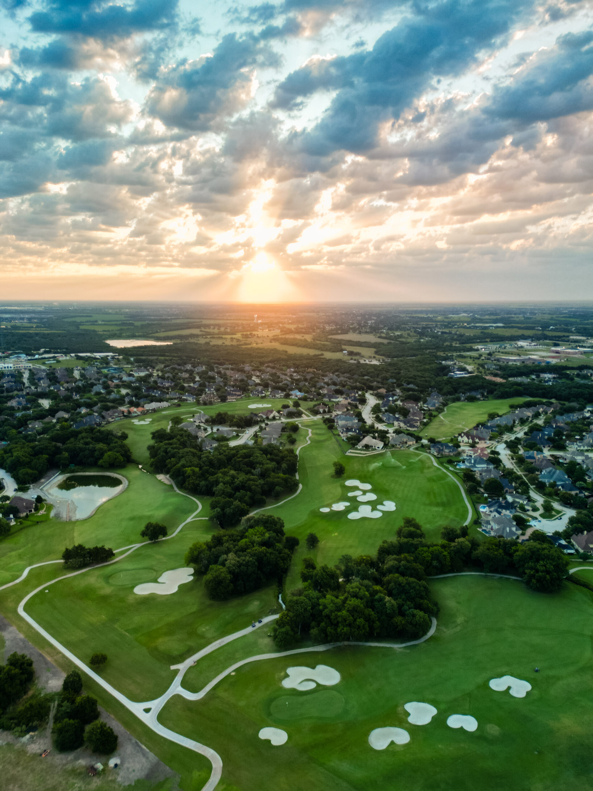 An aerial view of Buffalo Creek Golf Club showing several holes and the sunset.